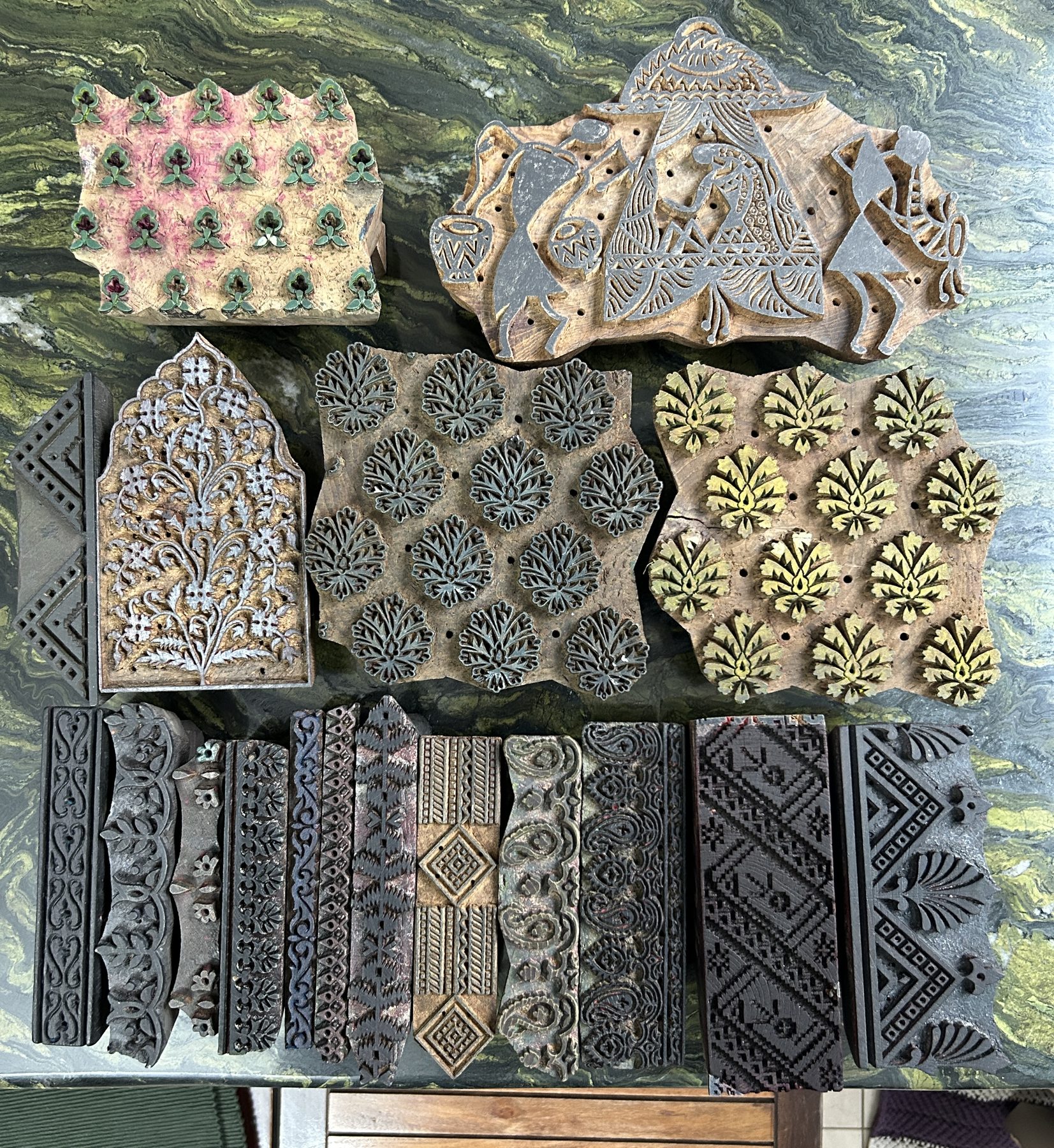 Hand-carved wooden printing blocks laid out on a table — florals, borders and geometric motifs